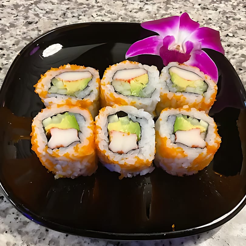 Six California sushi rolls with avocado, crab, and roe, garnished with a purple orchid.